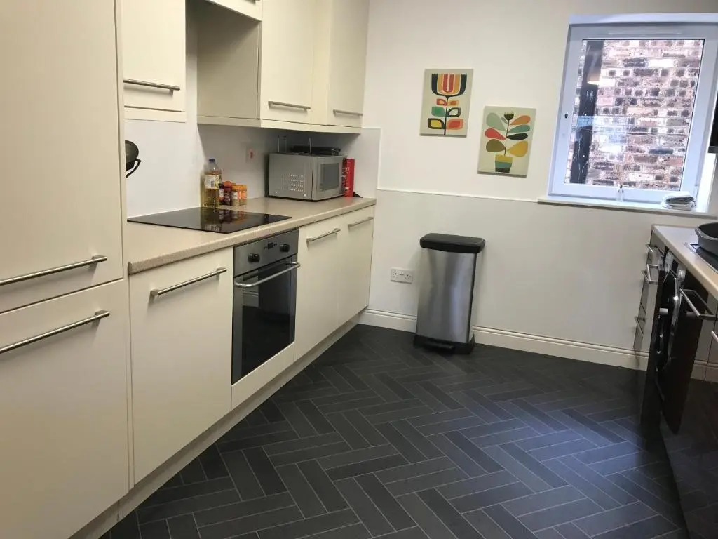 a kitchen with white cabinets and a tile floor at Town centre 4xbed 4xbath apartment in Elgin
