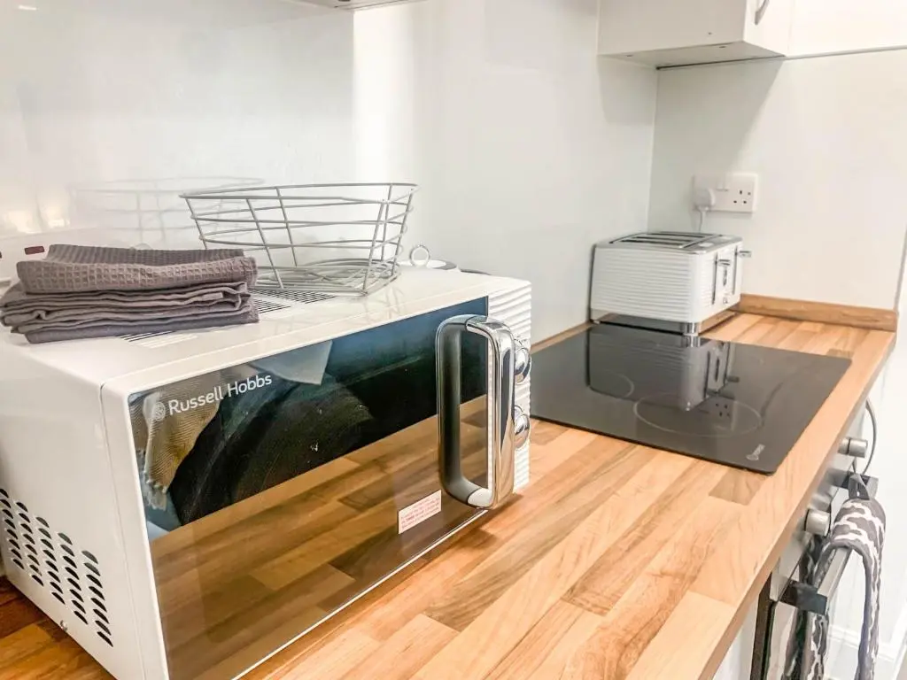a microwave oven sitting on top of a kitchen counter at The Rosebery Retreat By The Castle 1-Bed Apartment in Inverness