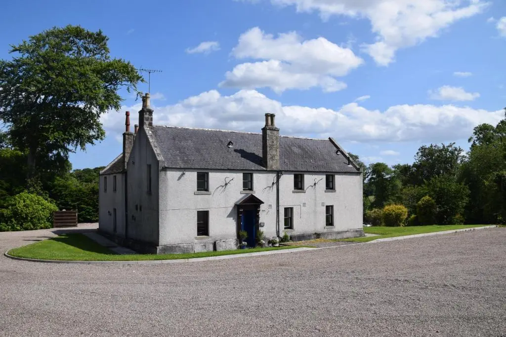 an old white house on the side of a road at Saplinbrae Hotel and Lodges in Mintlaw