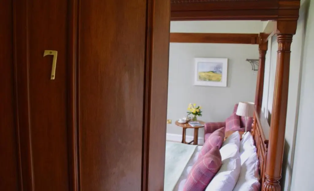 a door to a bedroom with a bed and a table at Saplinbrae Hotel and Lodges in Mintlaw
