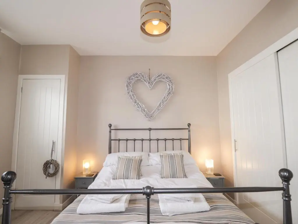 a bedroom with a bed with a heart sign on the wall at 18b New Street in Buckie
