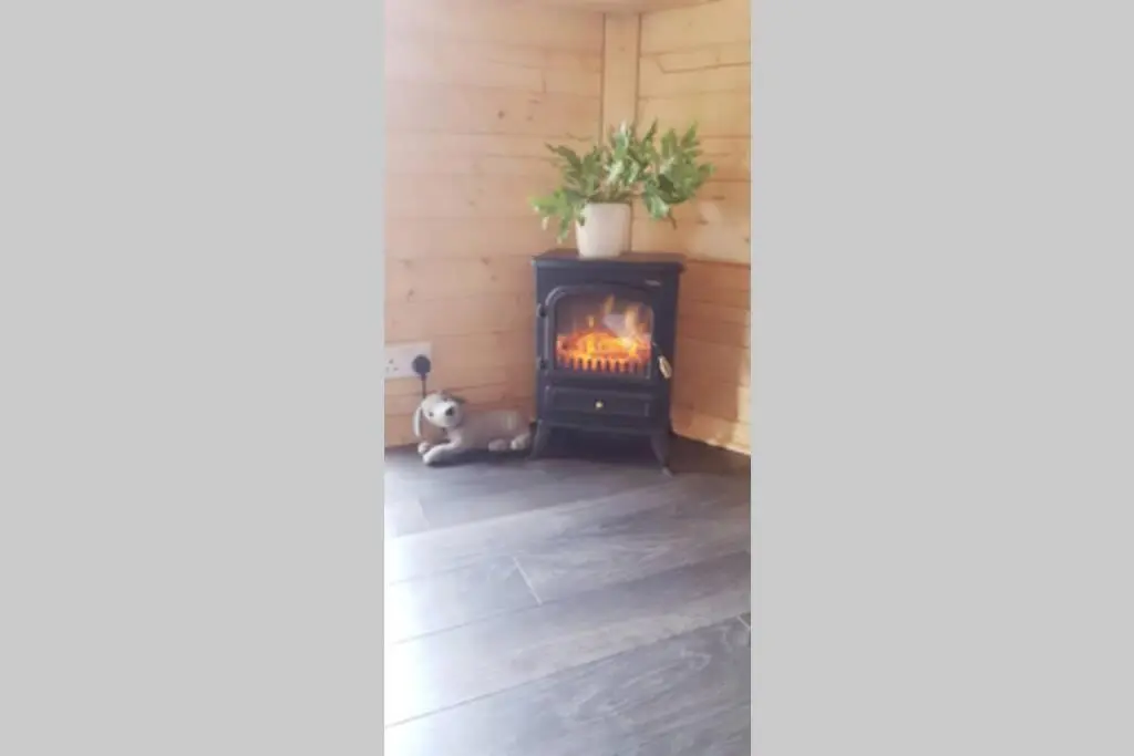 a wood burning stove in a corner of a room at Unique luxury cabin in Inverness