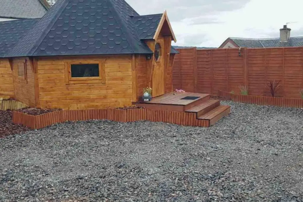 a backyard with a wooden cabin with a wooden fence at Unique luxury cabin in Inverness