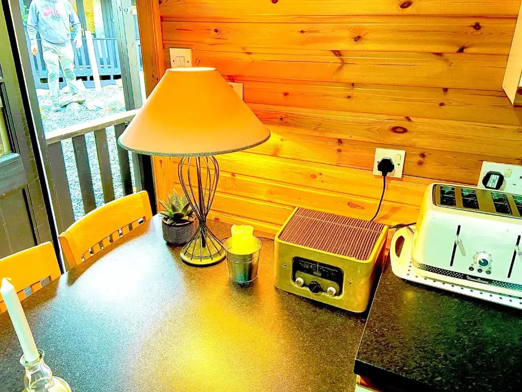 a table with a lamp and a toaster and a radio at Braemar Lodge Cabins Not for profit in Braemar
