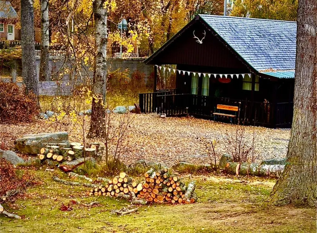 a pile of logs in front of a barn at Braemar Lodge Cabins Not for profit in Braemar
