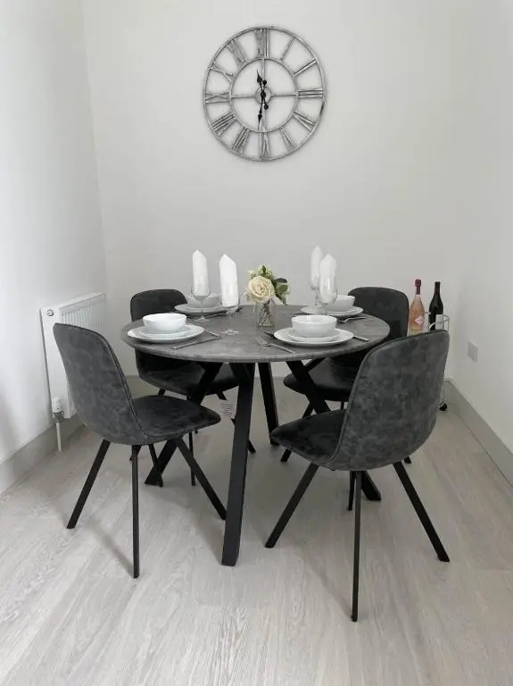 a dining room table with chairs and a clock on the wall at No 49 a spacious executive apartment in Inverness in Inverness