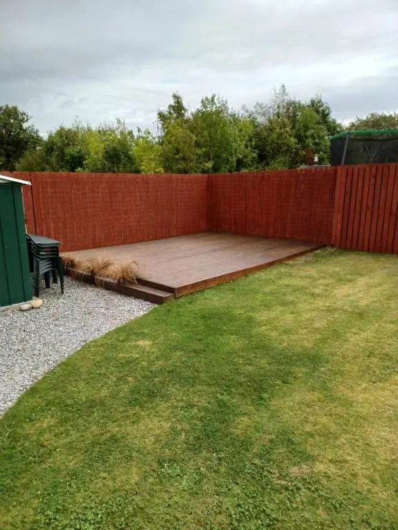 a dog laying on a patio next to a fence at Modern 2 Bedroom Semi detached House with own private driveway in Inverness