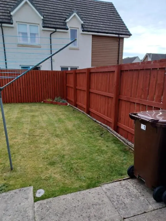 a fence in front of a house with a yard at Modern 2 Bedroom Semi detached House with own private driveway in Inverness
