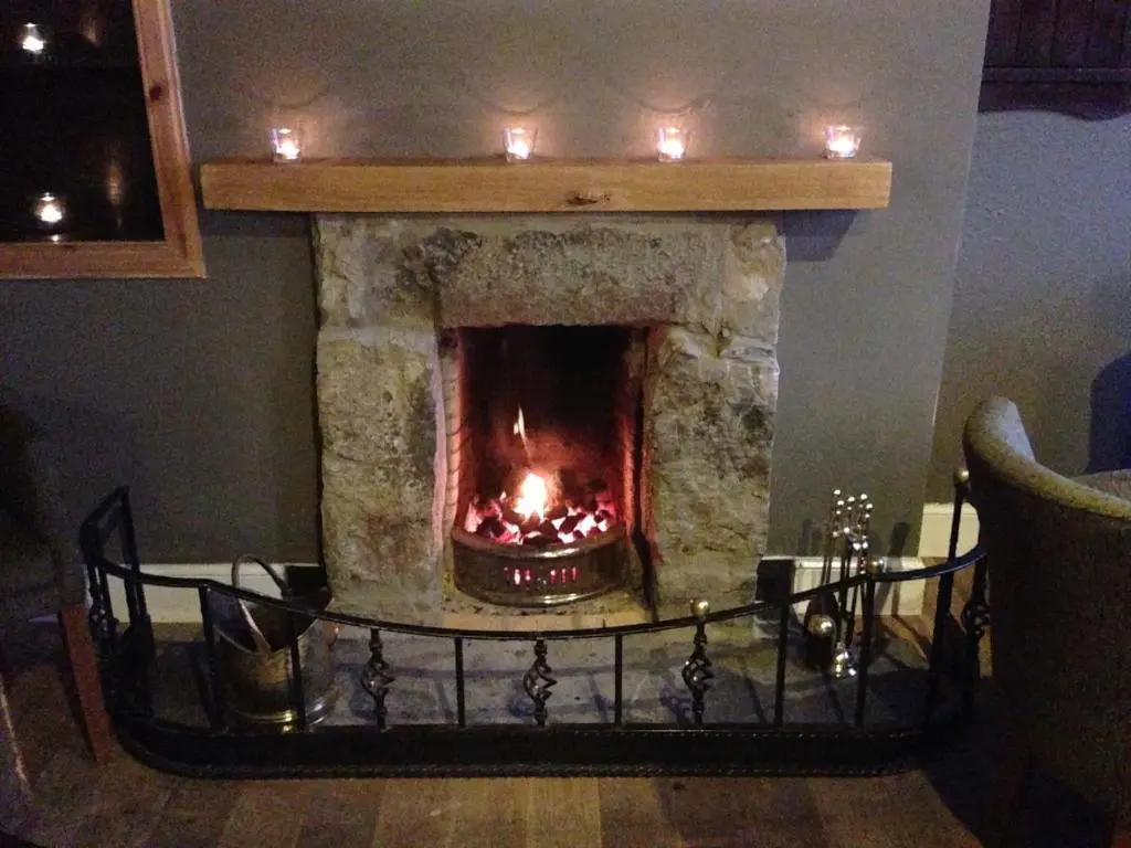 a fireplace in a living room with candles in it at The Ferry Boat Inn in Ullapool
