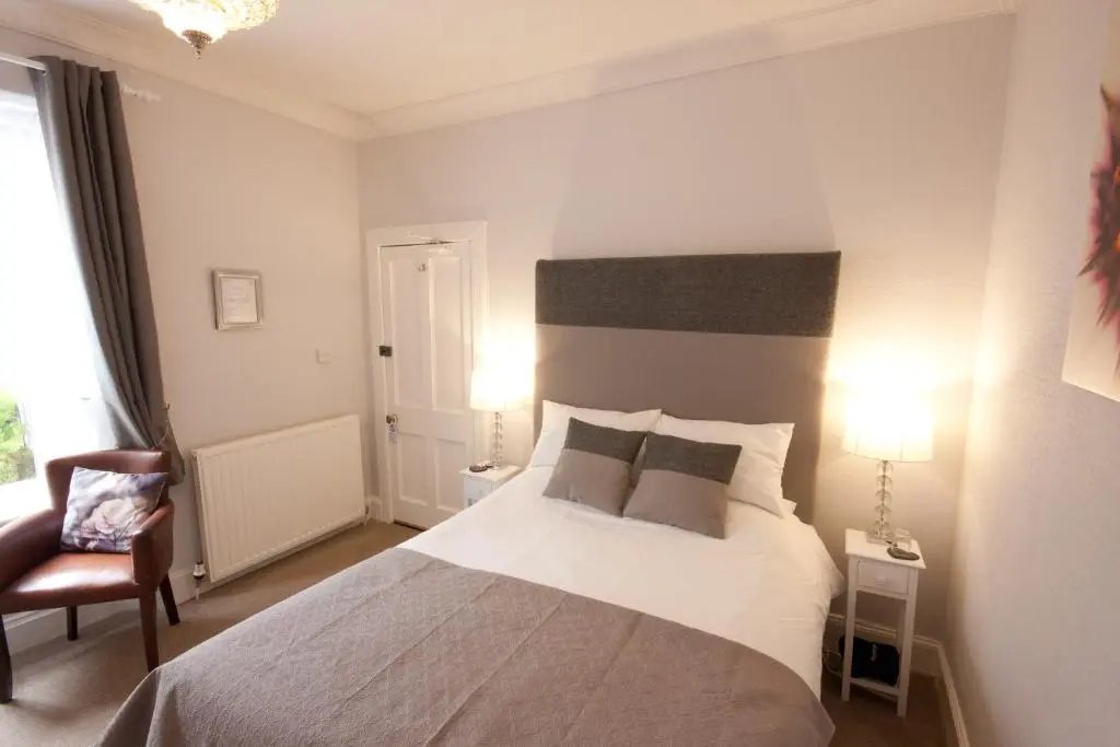 a bedroom with a large bed and a chair at The Ness Guest House in Inverness