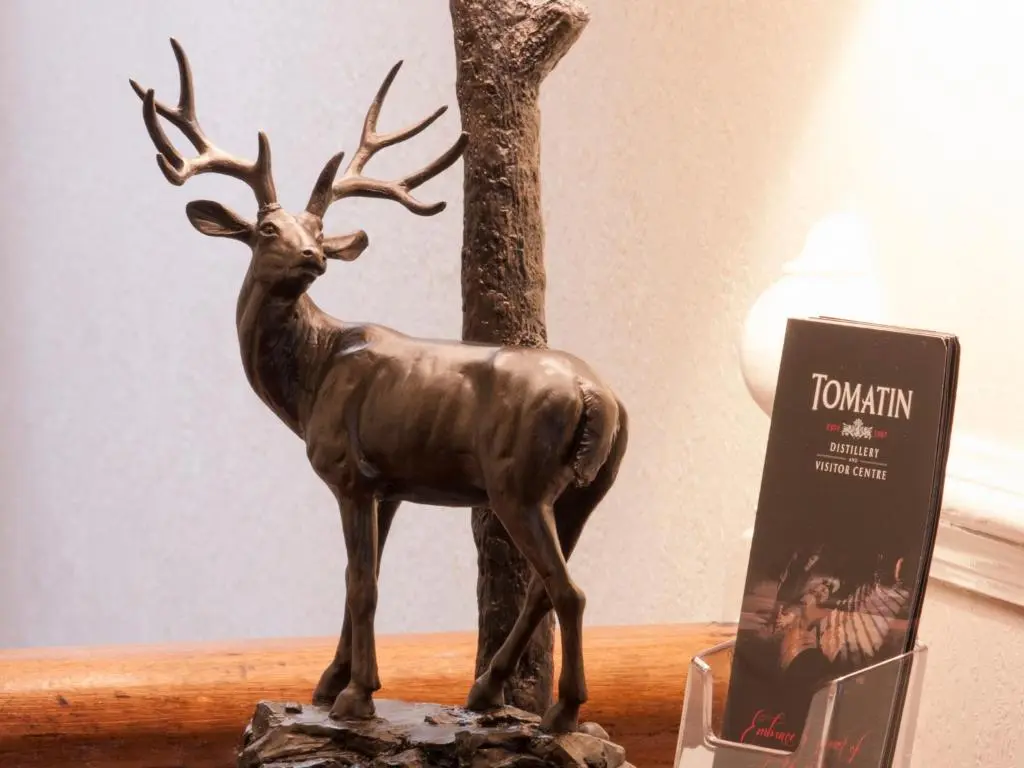 a statue of a deer on a table next to a book at The Ness Guest House in Inverness