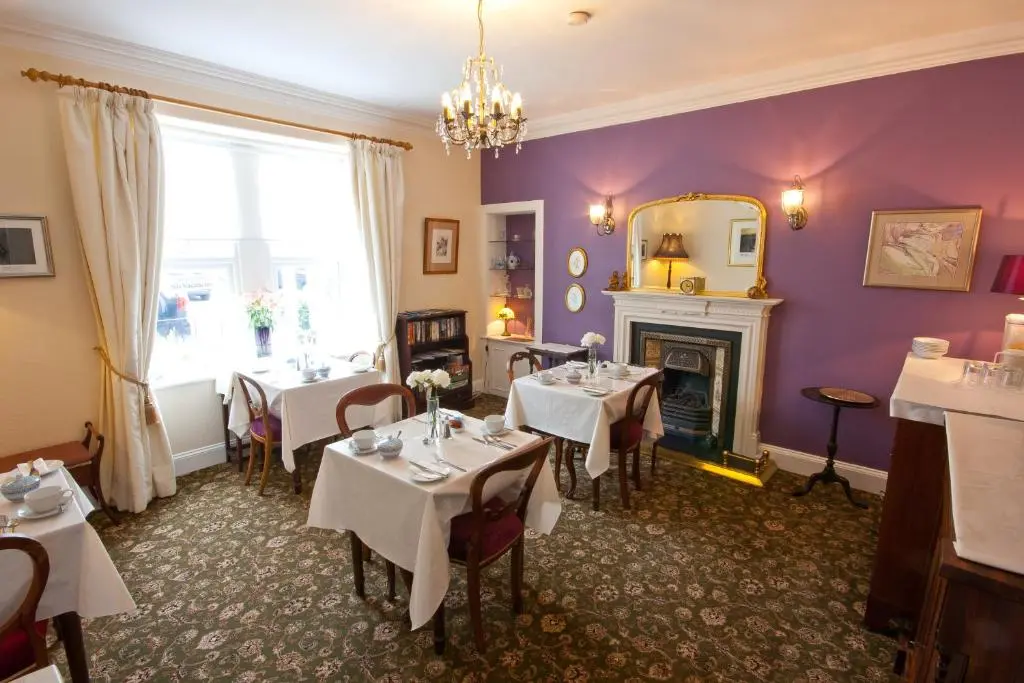 a dining room with tables and a fireplace at The Ness Guest House in Inverness