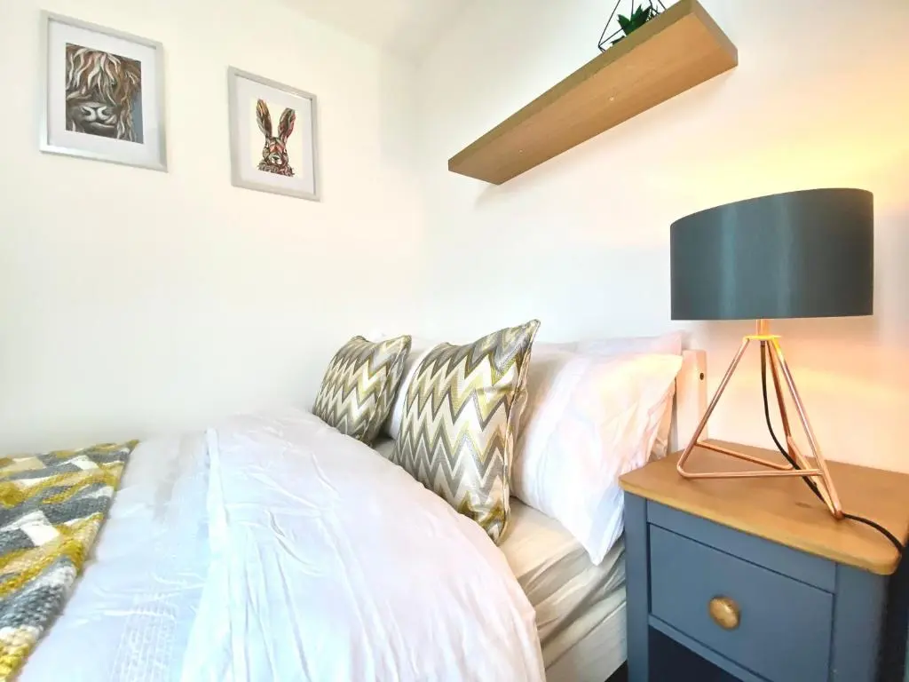 a bedroom with a bed and a lamp on a nightstand at Modern Spacious, Near Marina - Commerce Street, Lossiemouth - Free Parking, WiFi in Lossiemouth