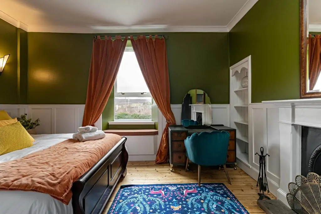 a bedroom with a bed and a desk and a window at 50TheHighstreet by The House of Danu in Kingussie