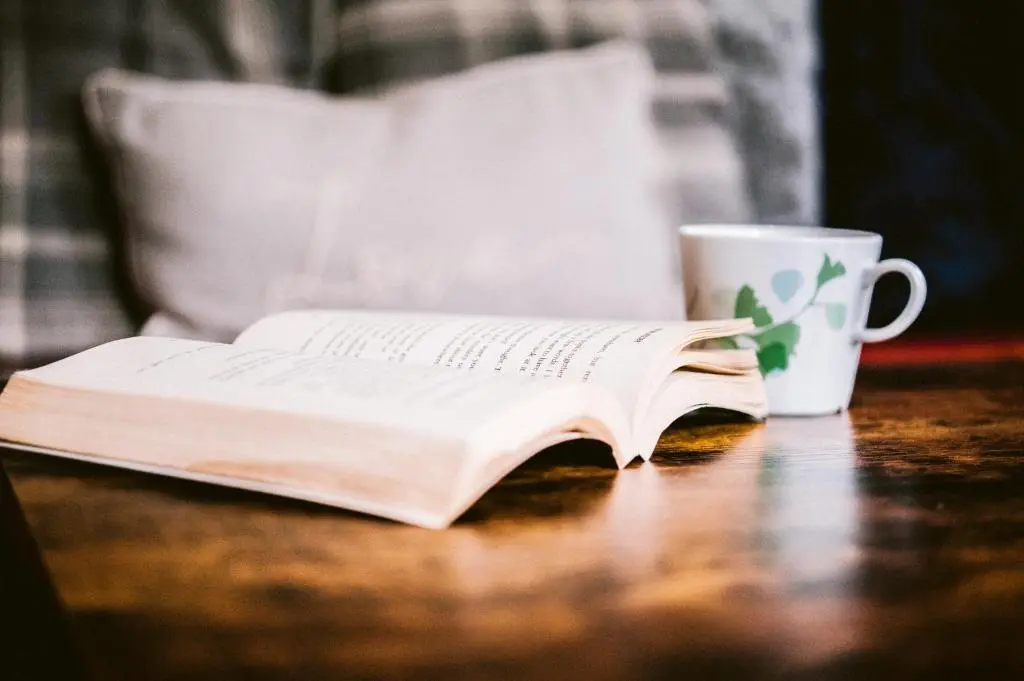 an open book on a table next to a coffee mug at Bright Star Lodge in Spean Bridge