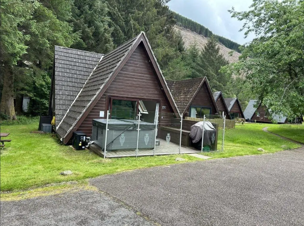 a small house with a gambrel roof on the grass at Bright Star Lodge in Spean Bridge