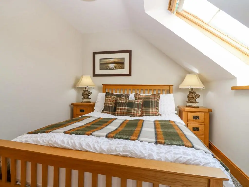 a bedroom with a wooden bed with two night stands at Stable Cottage in Inverurie