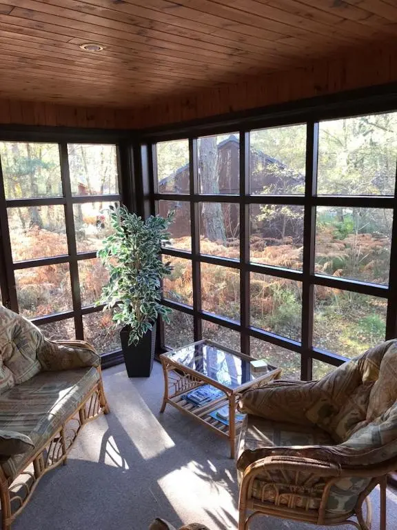 a screened in porch with two couches and a table at Tullochwood Lodges in Forres