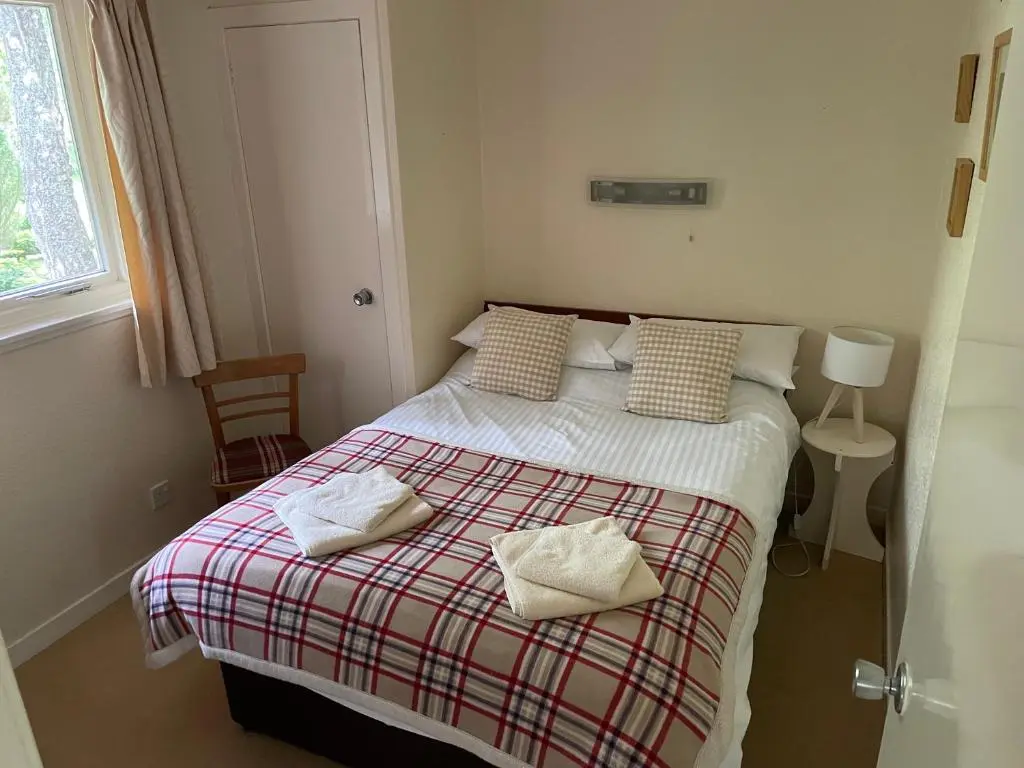 a bedroom with a bed with two towels on it at Tullochwood Lodges in Forres