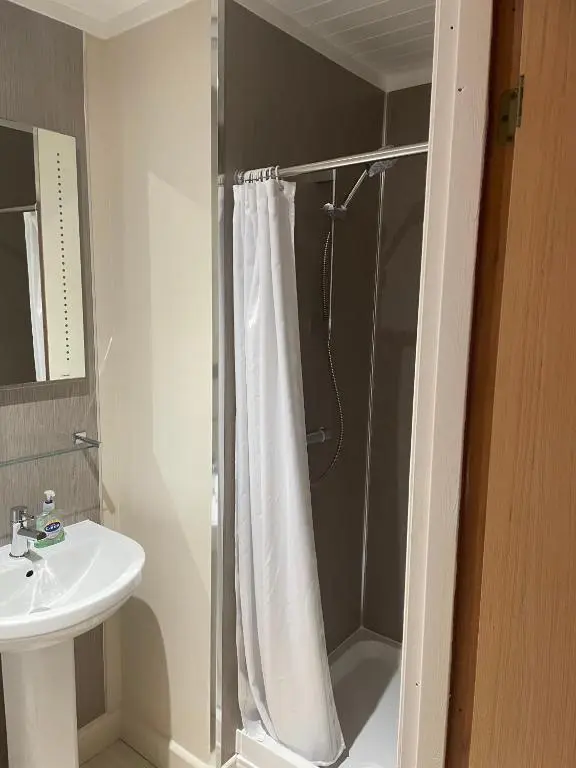 a bathroom with a shower curtain and a sink at Tullochwood Lodges in Forres