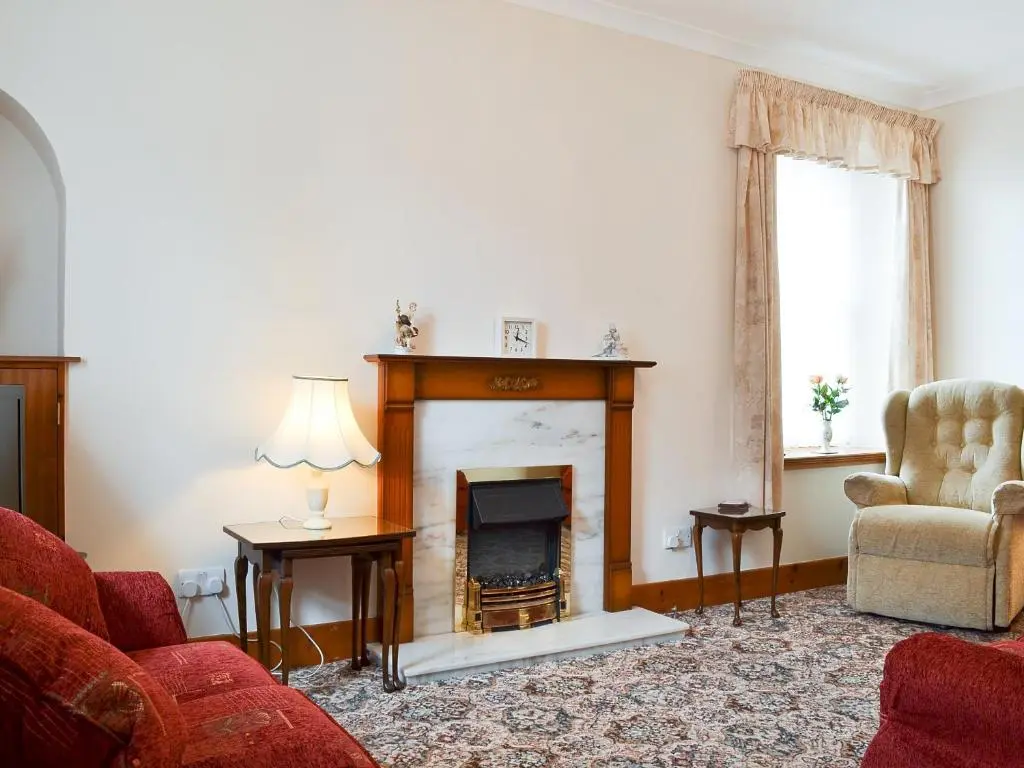 a living room with a fireplace and a couch and a chair at Number 12 in Portknockie