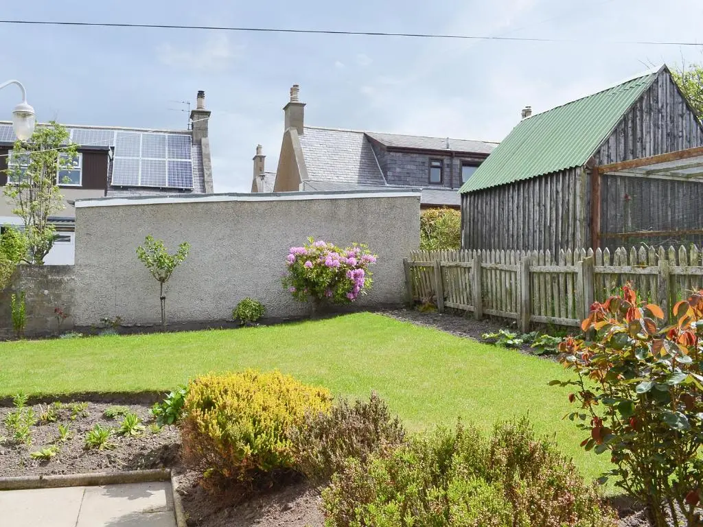 a backyard with a fence and a yard with flowers at Number 12 in Portknockie