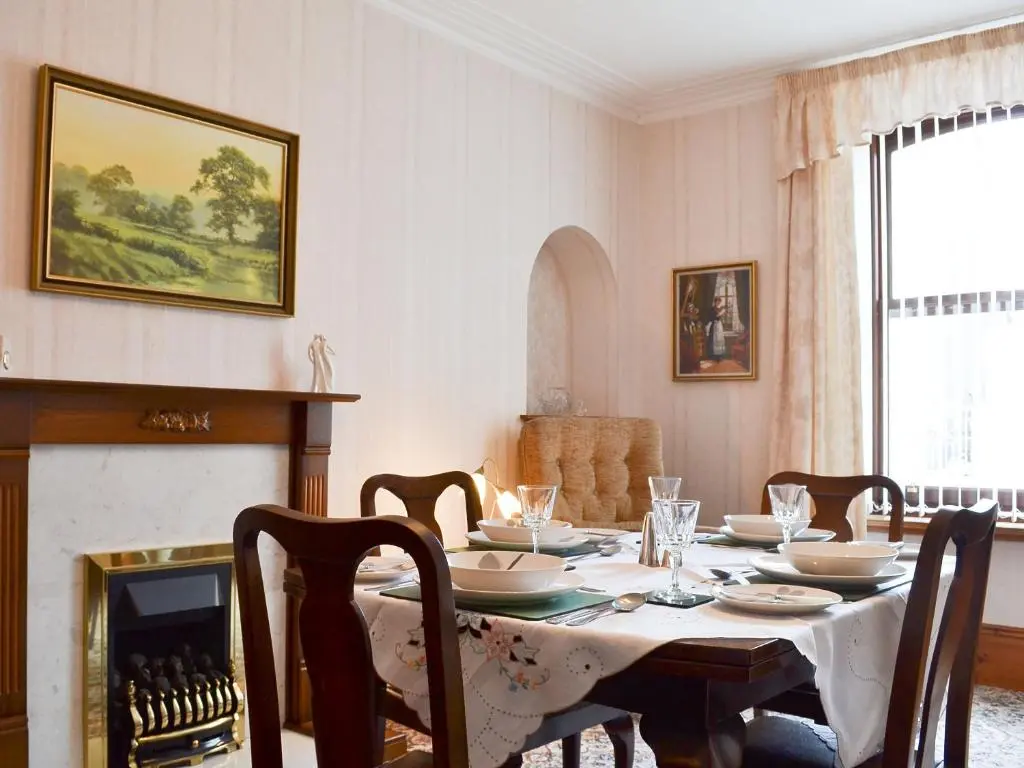 a dining room with a table and a fireplace at Number 12 in Portknockie