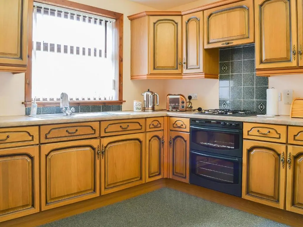 a kitchen with wooden cabinets and a black oven at Number 12 in Portknockie