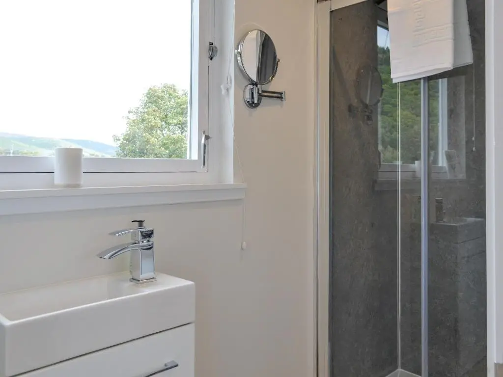 a white bathroom with a sink and a shower at Darroch View in Ballater
