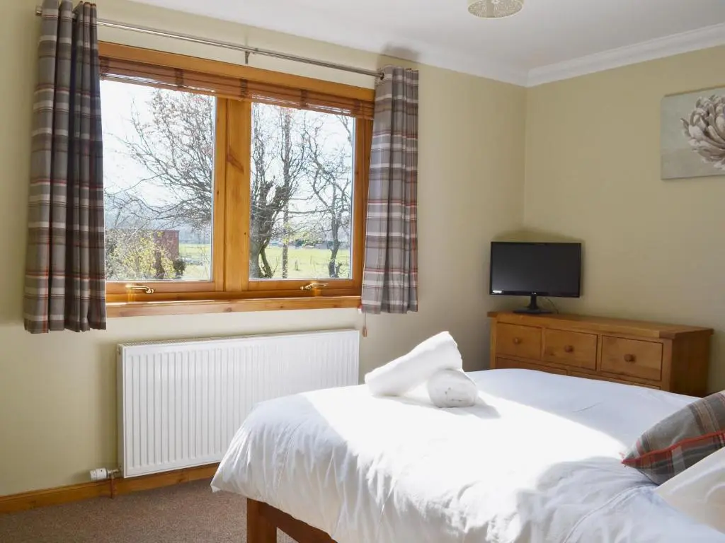 a bedroom with two beds and a window at North Lodge Gate House in Urray