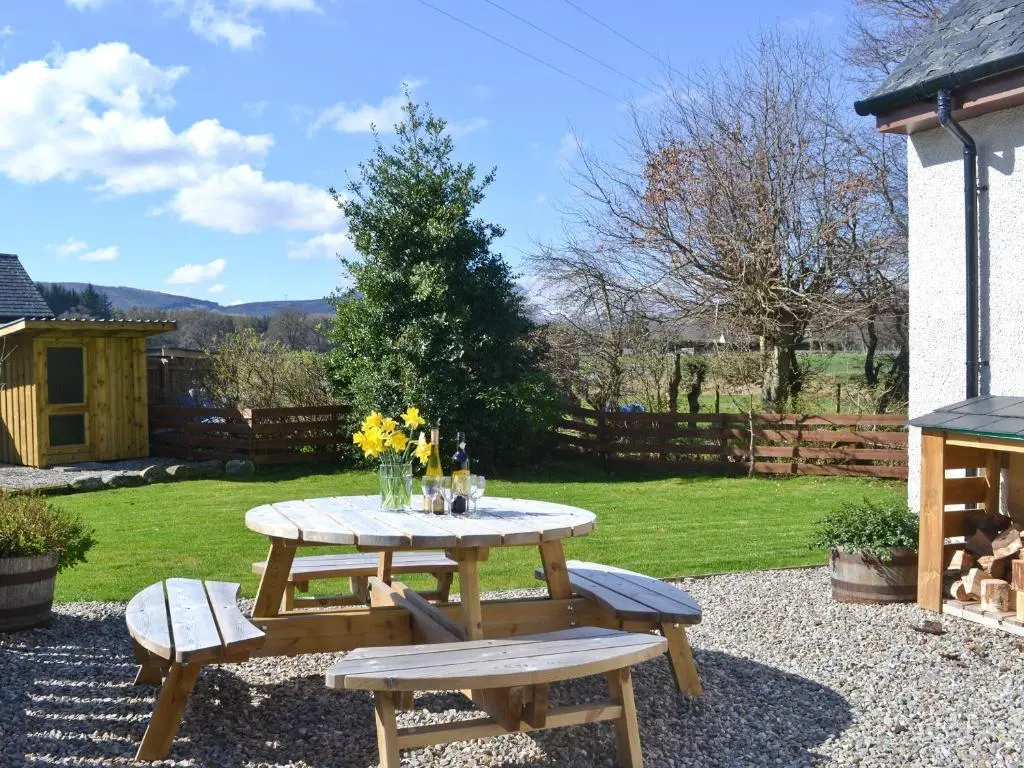 a picnic table and benches in a garden at North Lodge Gate House in Urray