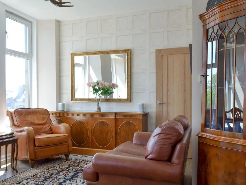 a living room with two chairs and a couch and a mirror at Inver House Apartment in Inverurie