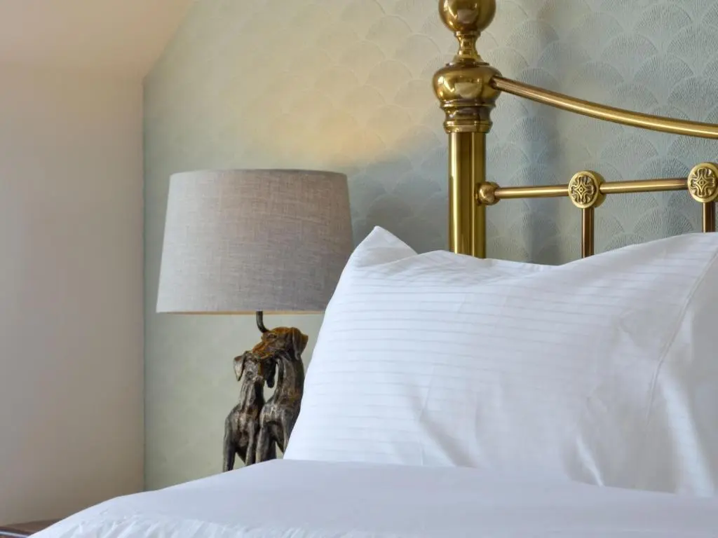 a bed with a white pillow and a lamp at Inver House Apartment in Inverurie