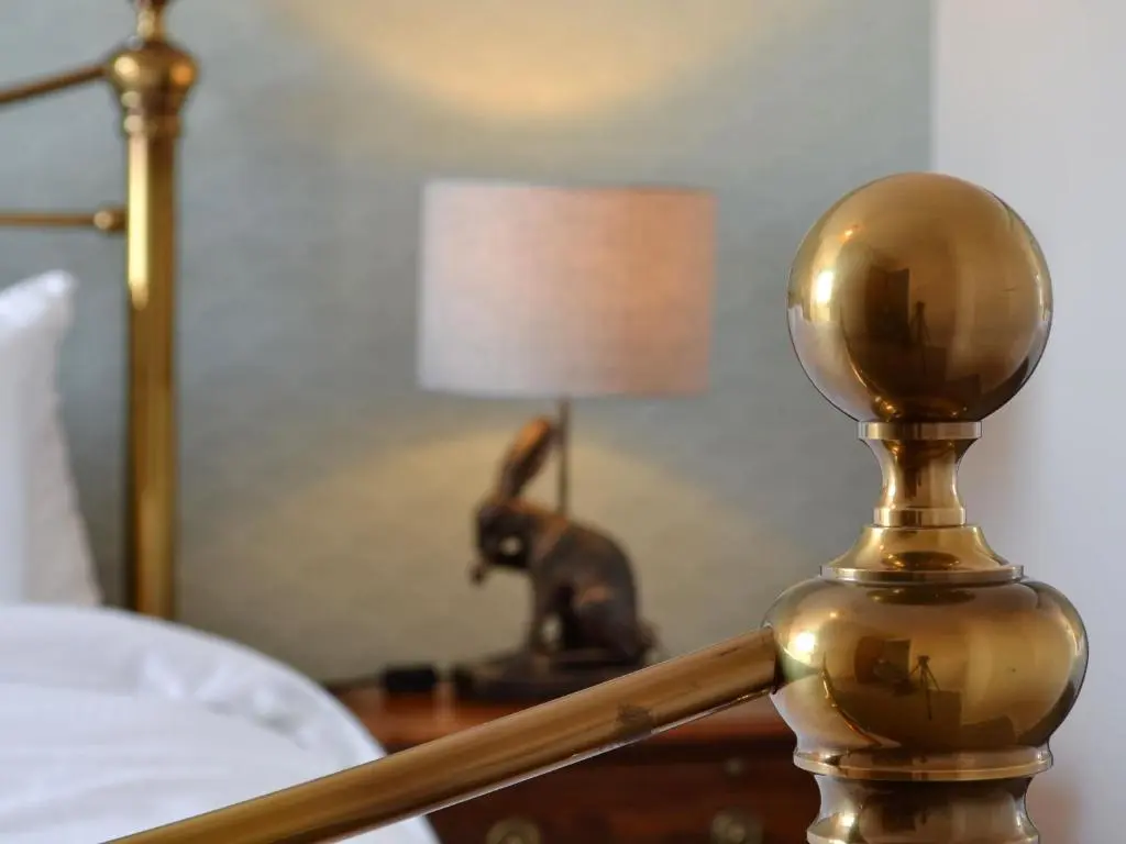 a gold lamp on a table next to a bed at Inver House Apartment in Inverurie