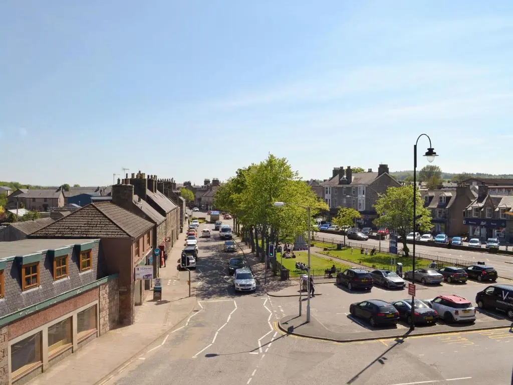 a city street with cars parked in a parking lot at Inver House Apartment in Inverurie