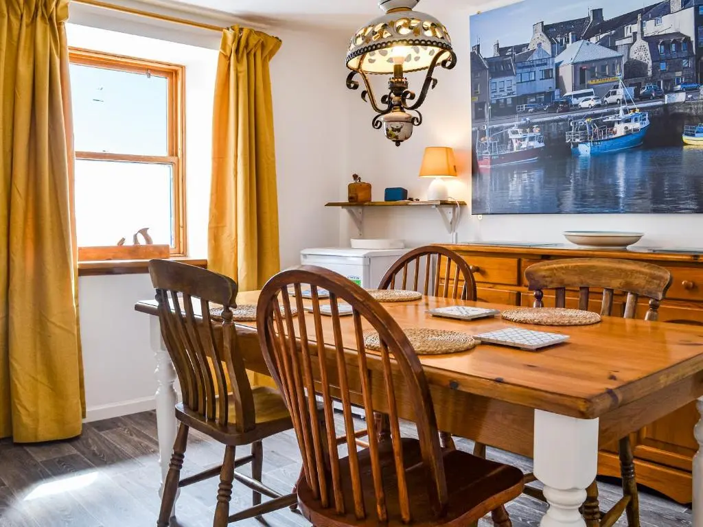 a dining room with a wooden table and chairs at Needle Cottage in Cullen
