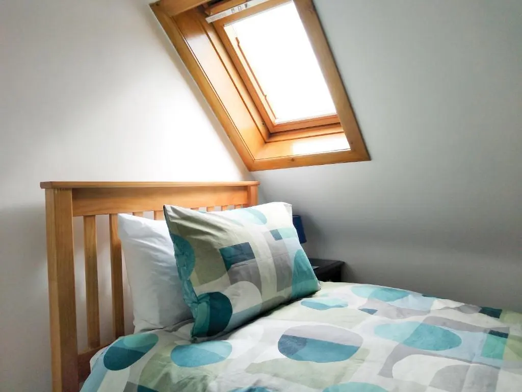 a bedroom with a bed with a window at Needle Cottage in Cullen