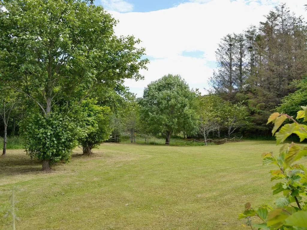 a large grass field with trees in the background at Woodside Cottage in Auchnastank