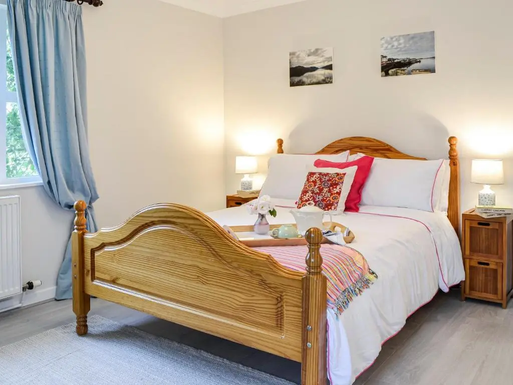 a bedroom with a bed with a wooden frame at Corrennie School Cottage in Whitehouse