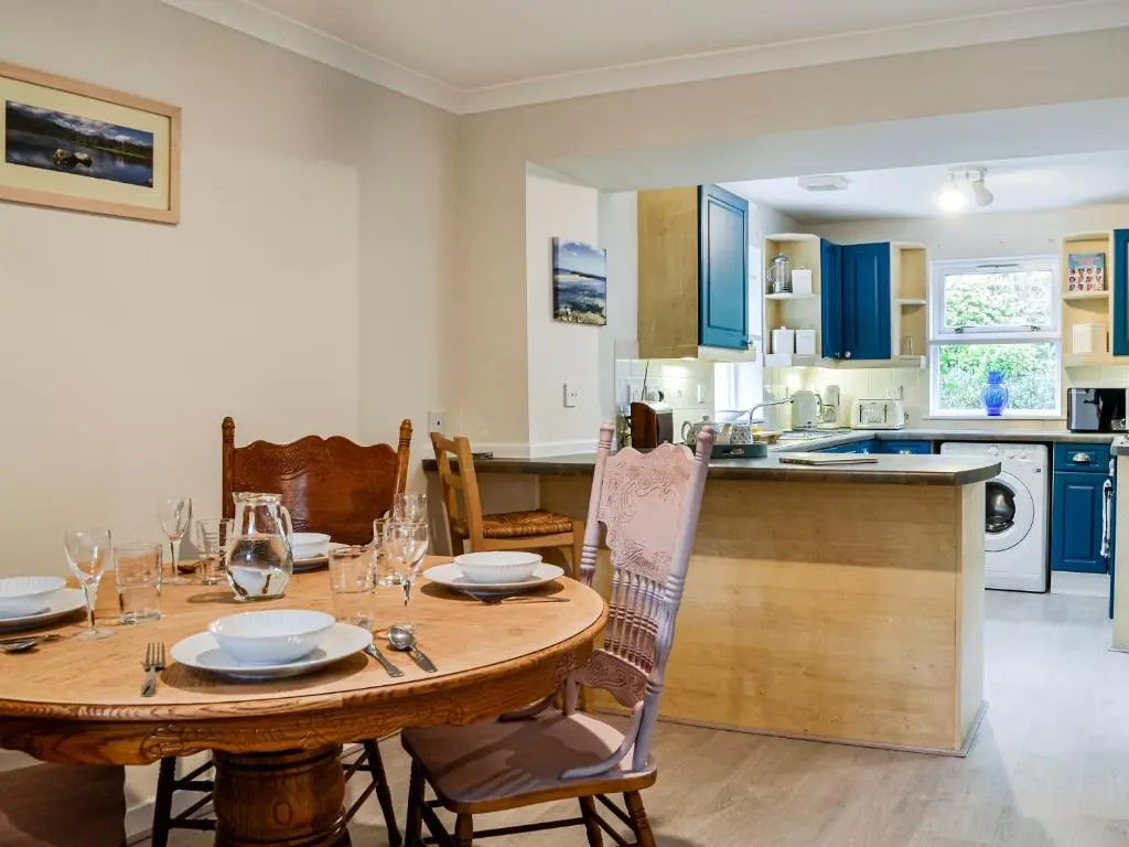 a kitchen and dining room with a wooden table at Corrennie School Cottage in Whitehouse
