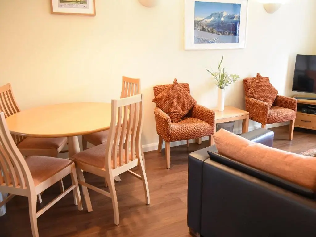 a living room with a table and chairs and a couch at Bonnie Doon in Aviemore