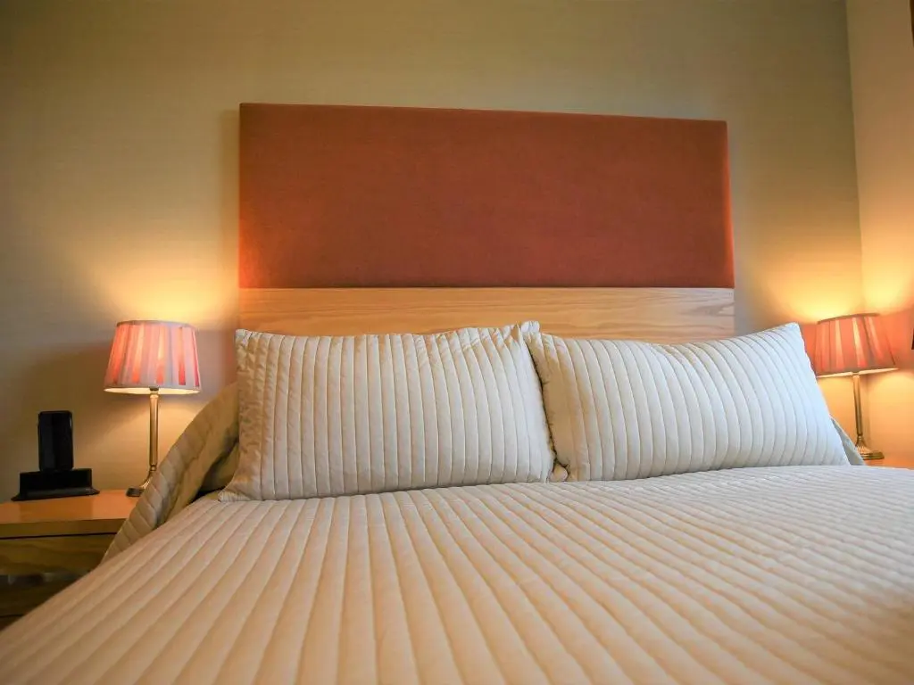 a bedroom with a large bed with two lamps at Bonnie Doon in Aviemore