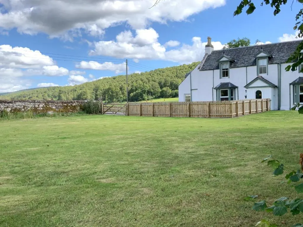 a white house with a fence and a yard at Darris Farmhouse in Lochend