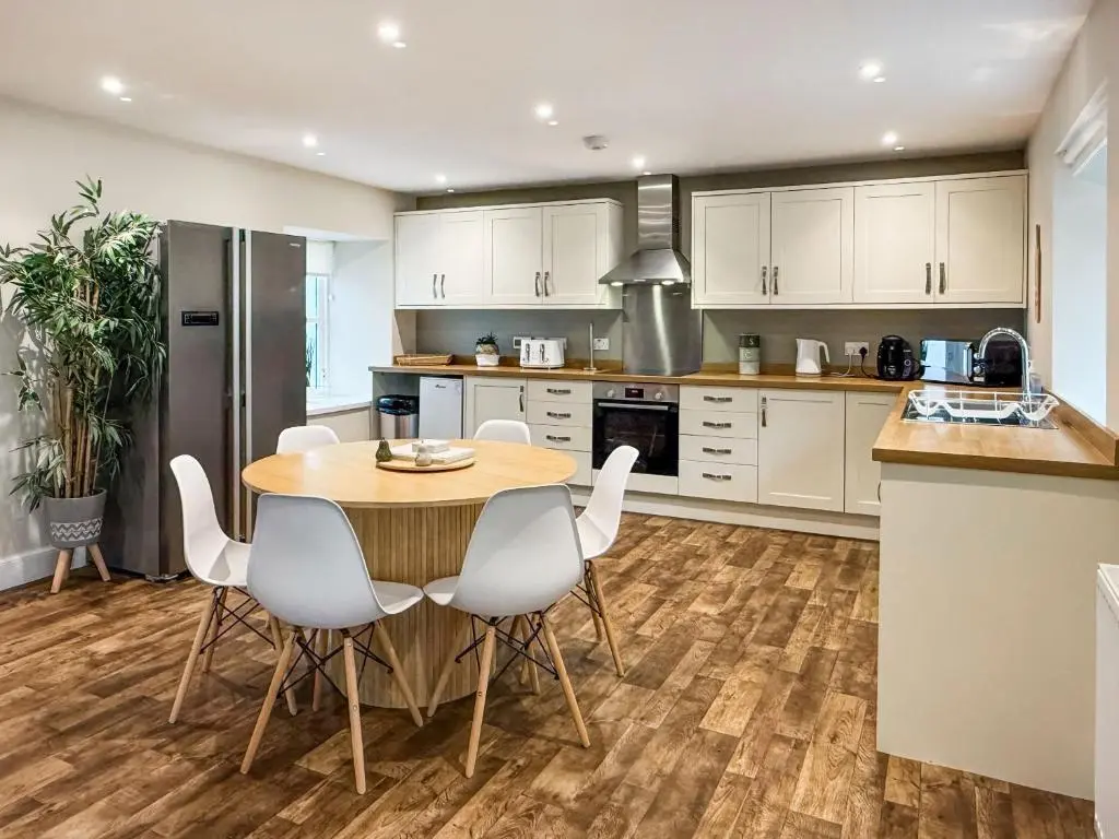 a kitchen with a wooden table and white chairs at Darris Farmhouse in Lochend
