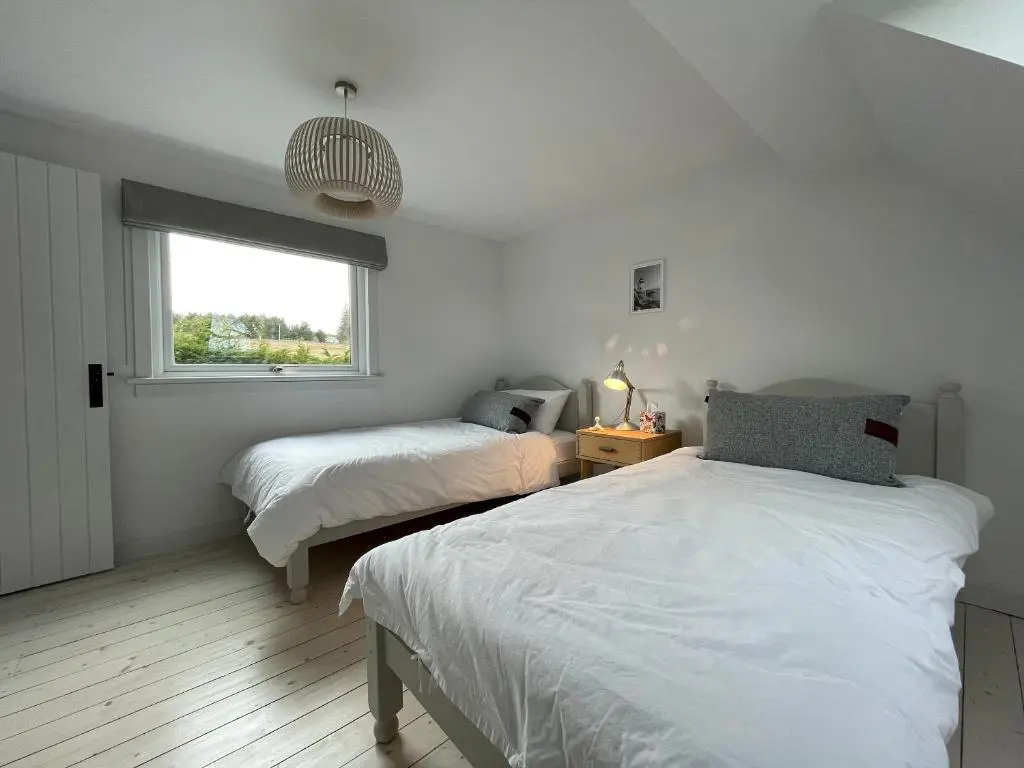 a bedroom with two beds and a window at Lower Hilton Cottage in Culrain
