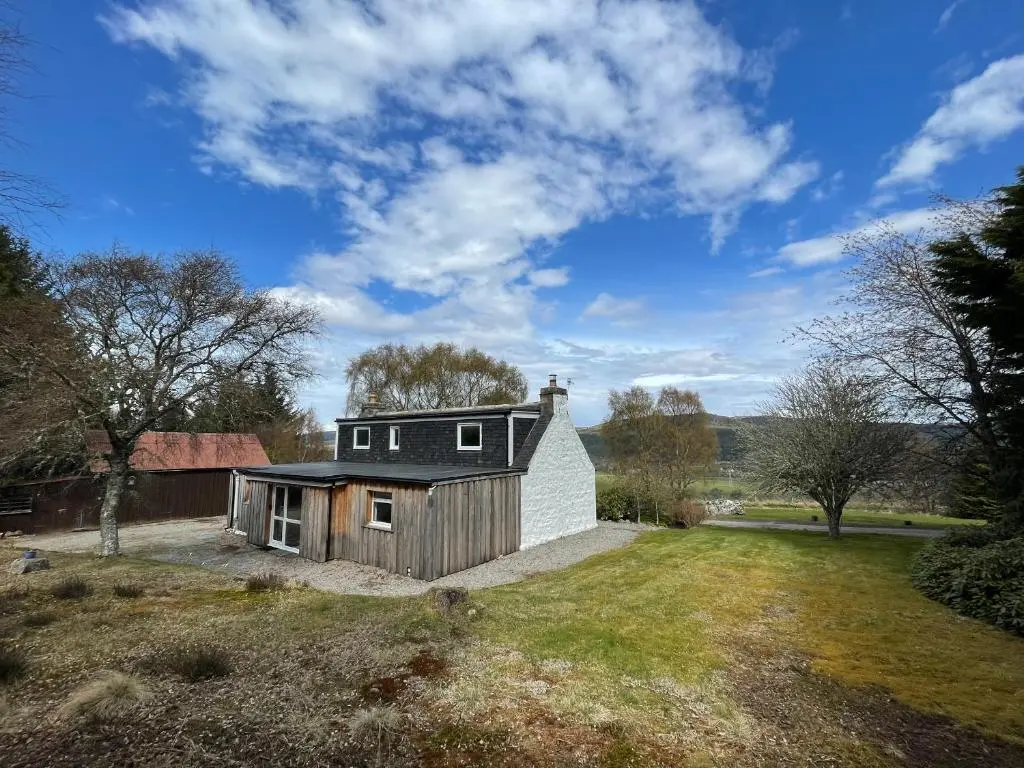 a house with a black roof on top of a yard at Lower Hilton Cottage in Culrain