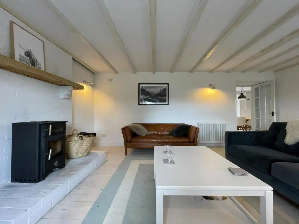 a living room with a couch and a fireplace at Lower Hilton Cottage in Culrain