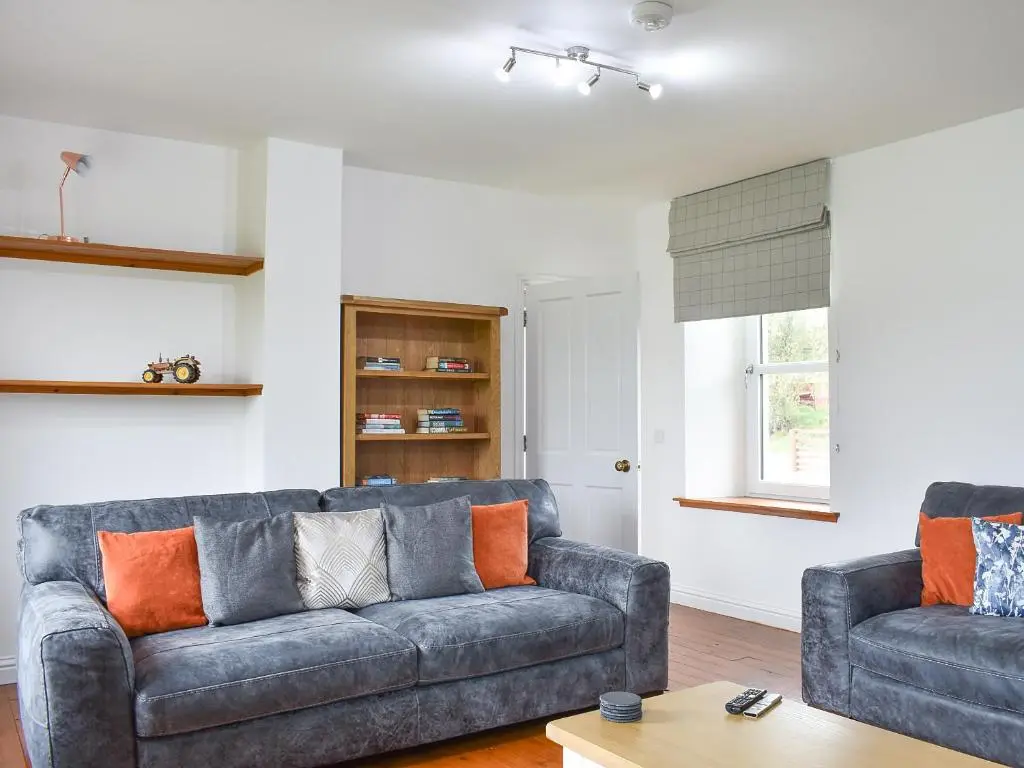a living room with two couches and a table at 1 Dalbuaick Farm Cottage in Carrbridge
