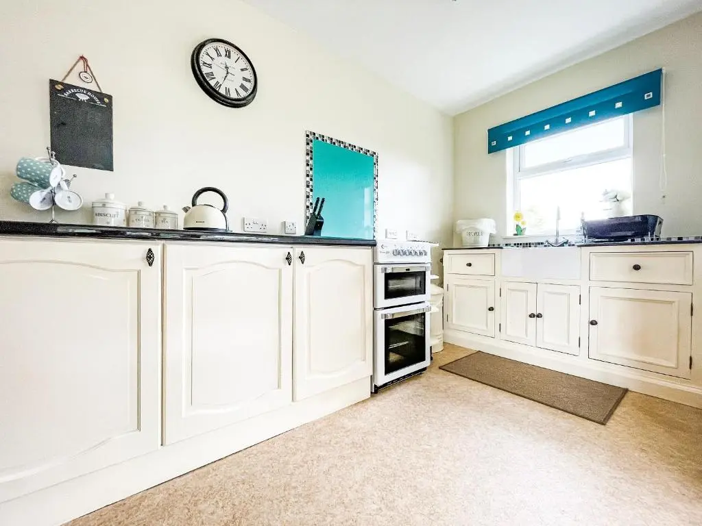a kitchen with white cabinets and a clock on the wall at Fourpenny Studio - Uk34745 in Embo