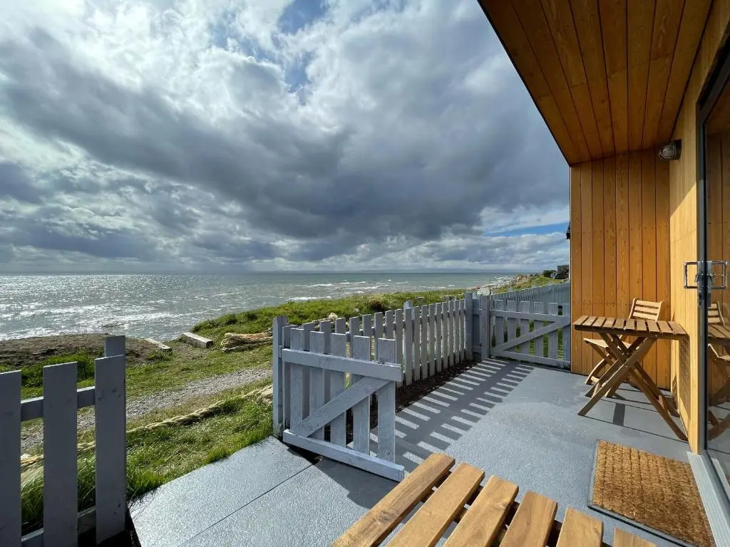 a porch of a house with a view of the ocean at Sunrise Summerhouse in Hilton of Cadboll